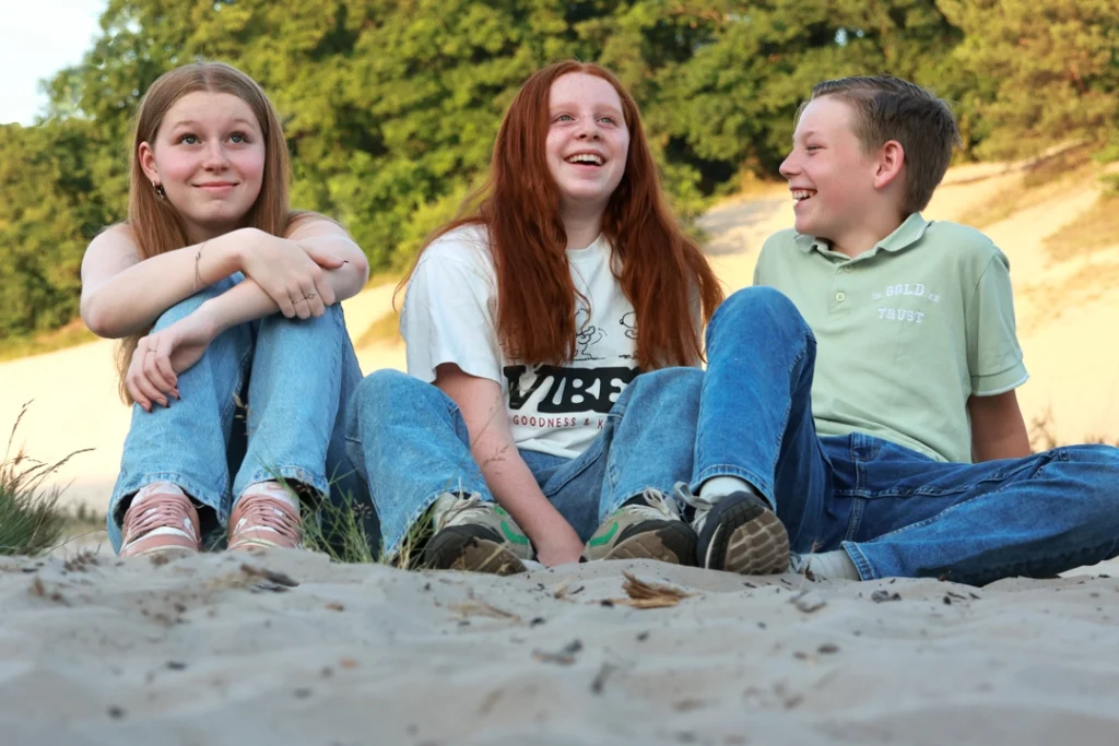 broer en zussen zitten in het zand portret fotografie
