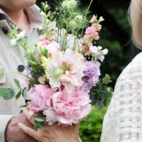 vrouw en man houden bruidsboeket vast